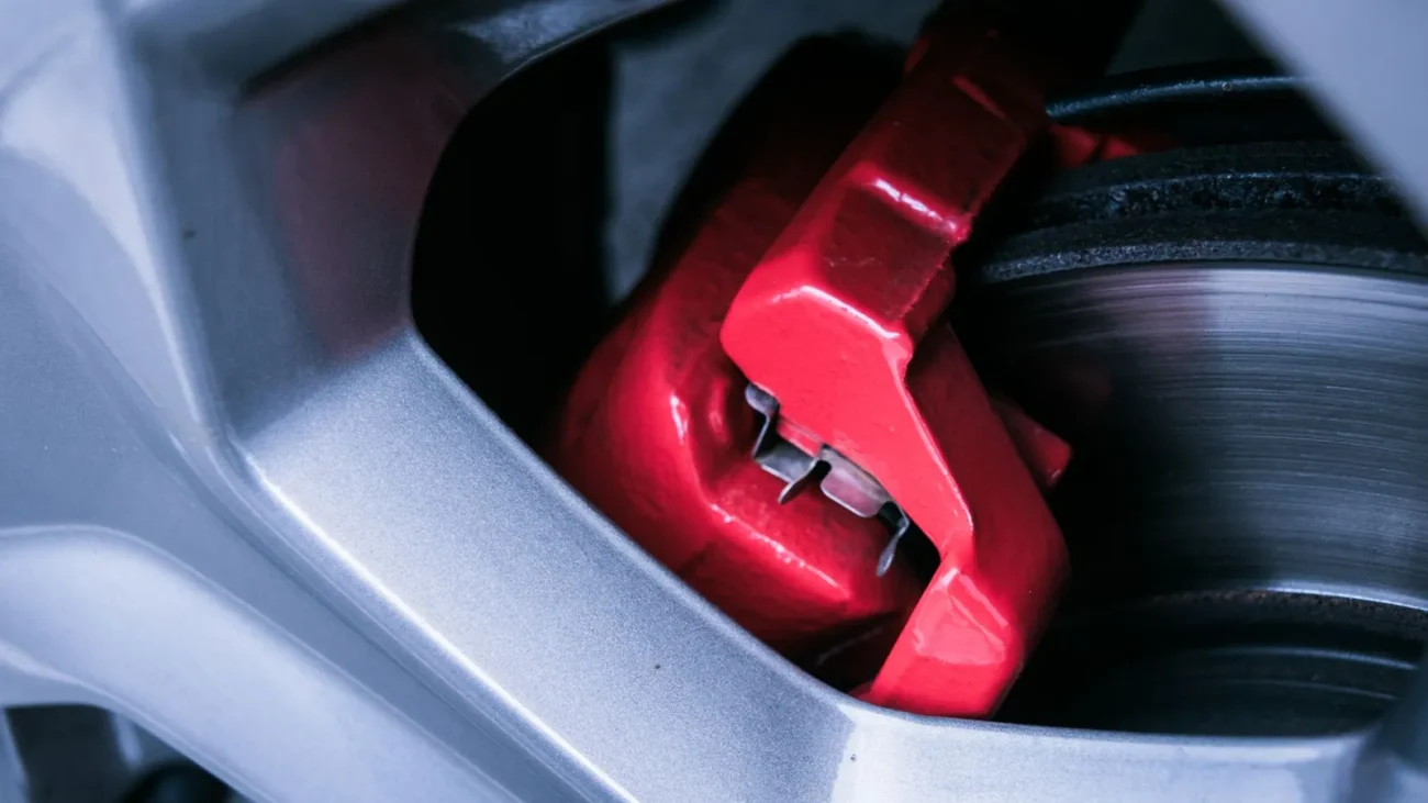 Red brake caliper behind an alloy wheel