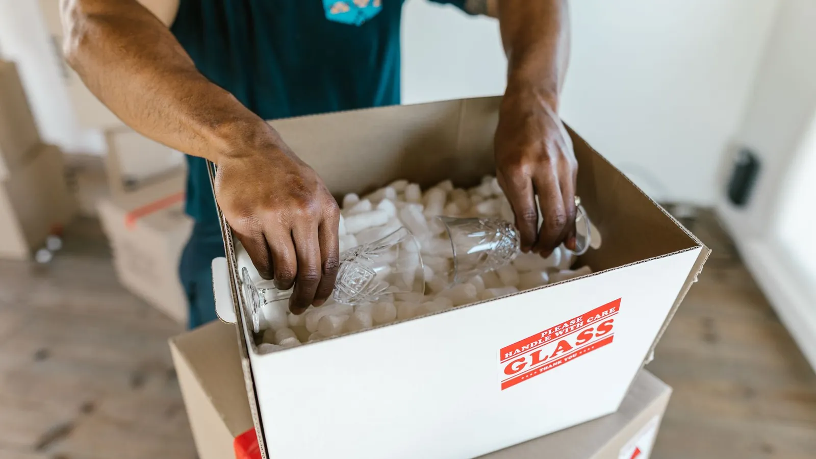 Hands packing a fragile item into a cardboard box