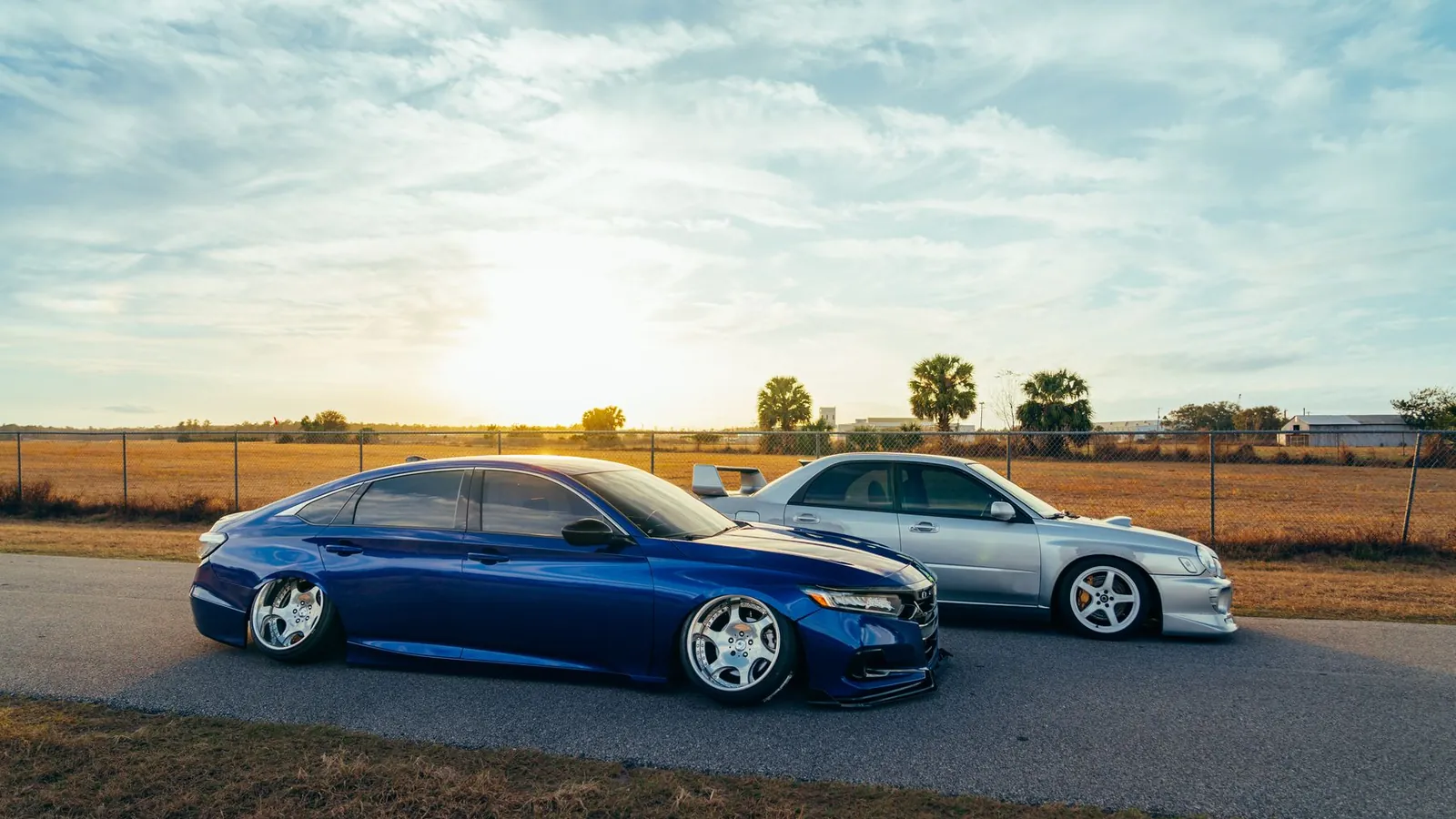 Two lowered modified cars on an open road