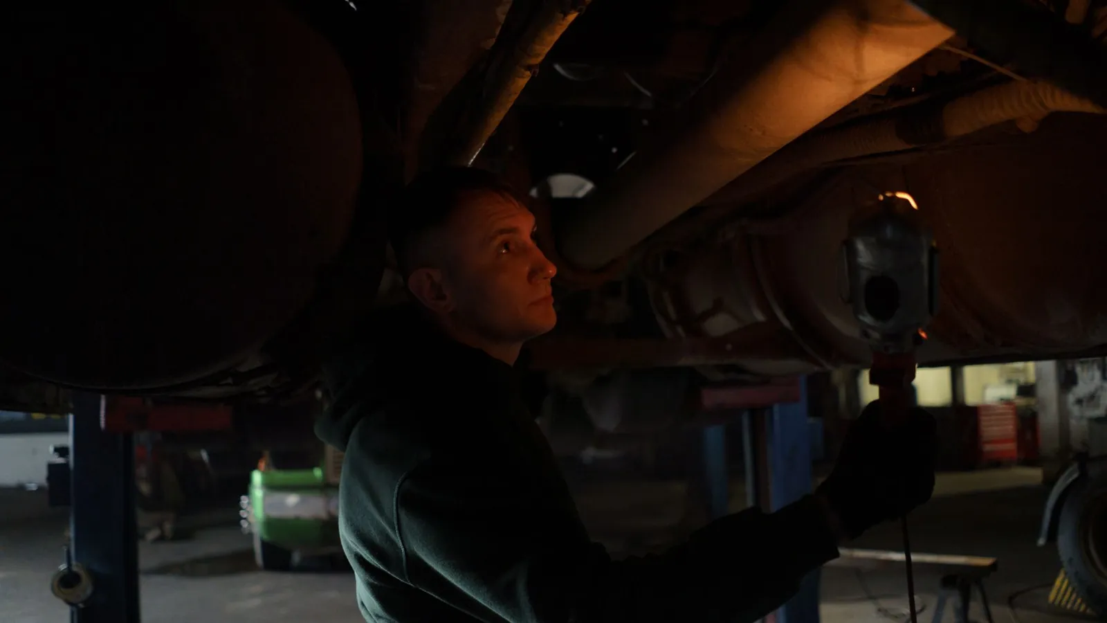 Mechanic checking the underside of a car with a light