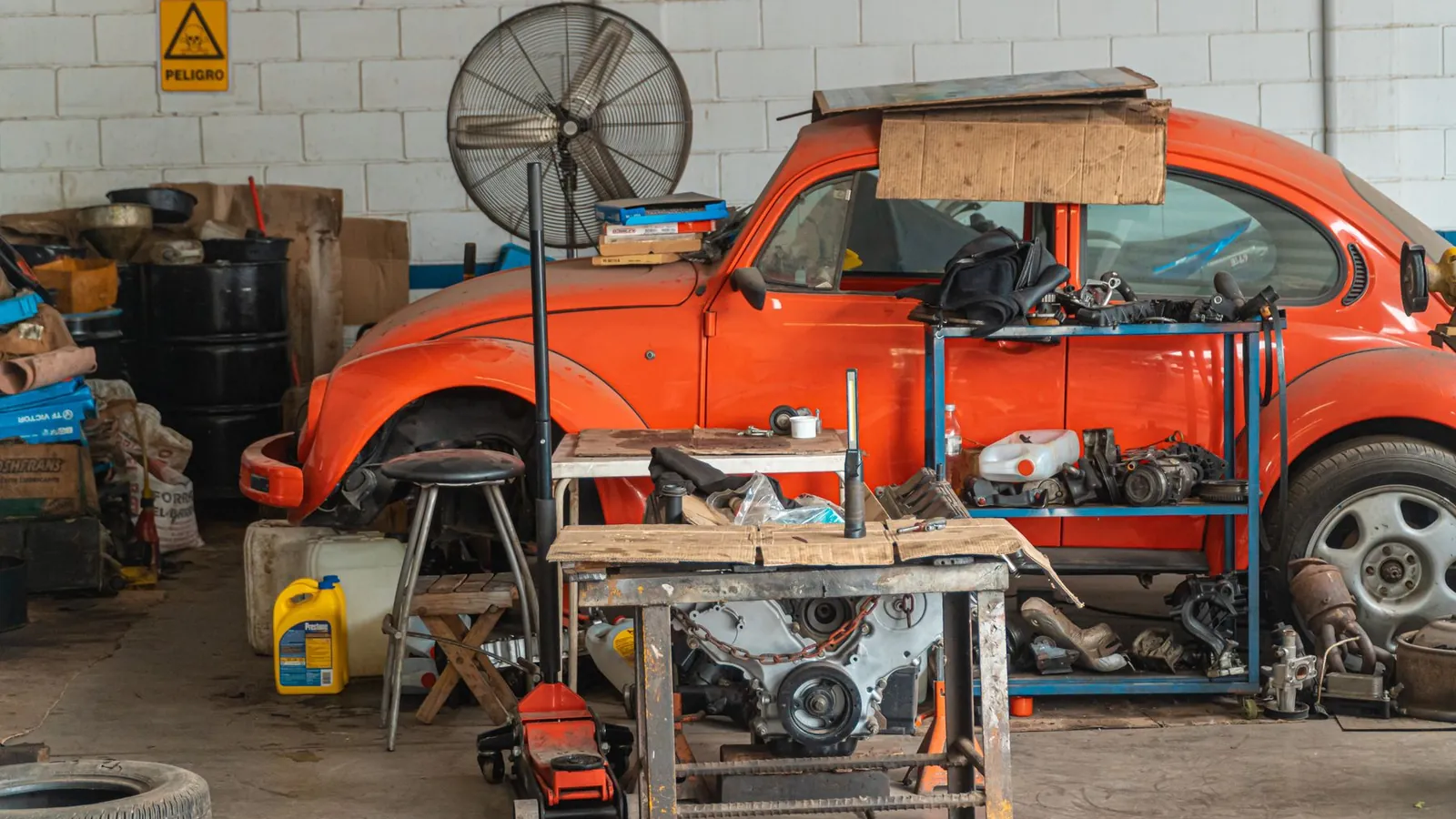 Classic car in a workshop surrounded by used parts